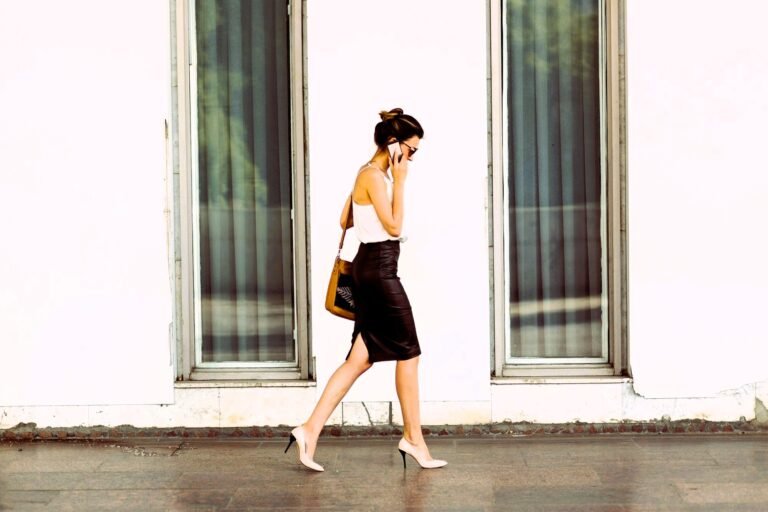 business woman wearing high heels walking on a sidewalk talking on mobile phone